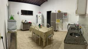 Una cocina con una mesa con sillas y un refrigerador. en Milagres, en São Miguel dos Milagres