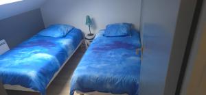 two beds in a bedroom with blue sheets at Studio N3 in Wingles