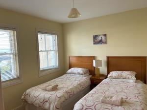a bedroom with two beds and two windows at Number 1 Bank House in Schull