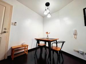 a dining room table with two chairs and a table with a vase at Gramercy Residences NEW! Tranquil 1BR Suite, 600mbps WIFI, Netflix & FREE Amenities in Manila