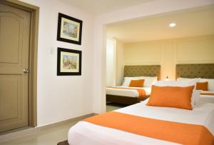 a hotel room with two beds with orange pillows at Hotel Cafe Cafe Avenida in Armenia