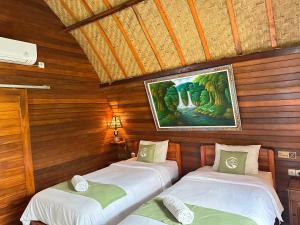 two beds in a room with a painting on the wall at Putra Bali Villa by Antara in Klungkung +39 photos