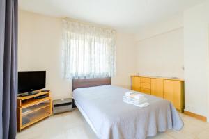 a small bedroom with a bed and a television at A quelques pas de la mer in Roquebrune-Cap-Martin
