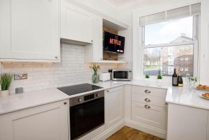 een keuken met witte kasten, een magnetron en een raam bij Fishergate Bar Apartment sleeps 4 in York