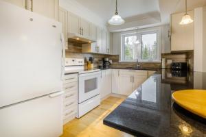 a kitchen with white appliances and a wooden table at Chalet Entre Ciel et Fleuve, SPA, 5 CH, 5 SDB in Petite-Rivière-Saint-François +9 photos