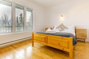 a bedroom with a bed and two large windows at Chalet Entre Ciel et Fleuve, SPA, 5 CH, 5 SDB in Petite-Rivière-Saint-François