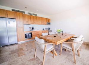cocina con mesa de madera con sillas y nevera en La Amada Residences Private Beach Getaway with Pools & Gym, en Cancún 134 fotos más