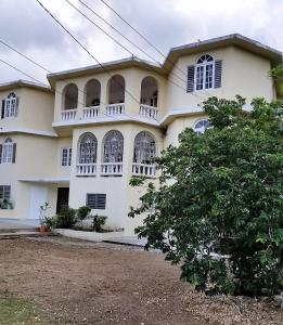 a large white building with windows and a tree at Maranatha Close in Montego Bay +7 photos