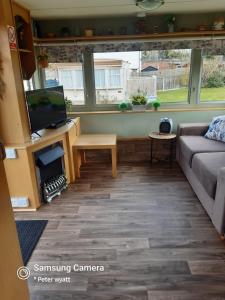 a living room with a couch and a tv at Gina's Static caravan,118 Sandsgate in Hemsby