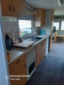 a kitchen with a sink and a stove top oven at Gina's Static caravan,118 Sandsgate in Hemsby