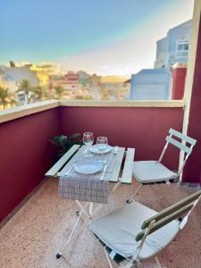 a table with two chairs and wine glasses on a balcony at Brisas de Sardina Apartment in Sardina