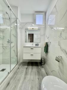 a white bathroom with a sink and a shower at Brisas de Sardina Apartment in Sardina