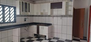 a kitchen with white cabinets and a checkered floor at Casa para a COP 30 in Barcarena