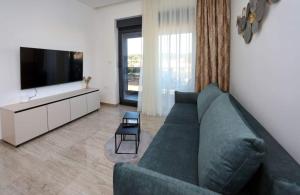 a living room with a green couch and a flat screen tv at Sunny Oasis in Bibinje