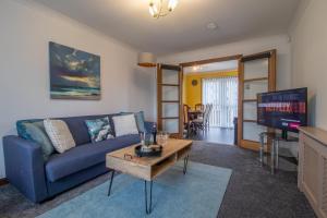 a living room with a blue couch and a table at Ideal Contractor Stay 2-Bed Near Glasgow Fort in Garthamlock