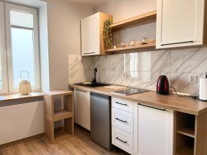 a kitchen with white cabinets and a sink and a window at Kawalerka Łódź 51 in Łódź
