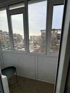 una stanza vuota con tre finestre e una sedia di 1 комнатная квартира город Экибастуз a Ekibastuz
