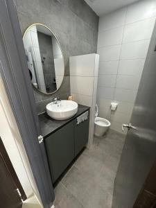 a bathroom with a sink and a mirror and a toilet at Podium Premium Homestay in Kuching