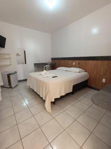 a room with a bed with a table in it at Pousada Lorenise in Guriri