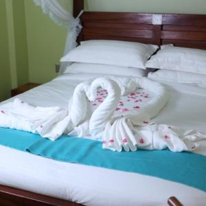 a bed with white blankets and pillows on it at Bedarin Hotel Limited in Ruiru