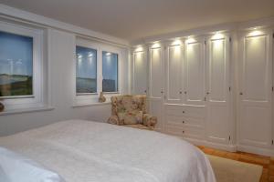 a bedroom with a bed and a chair and windows at Luxus Sönshörn 20 in Munkmarsch +6 photos