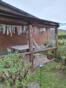 eine Terrasse mit einer Schaukel, einem Tisch und Stühlen in der Unterkunft Casas Buen Camino y La Magia in Sierra de la Ventana