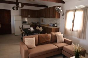 a living room with a brown couch and a kitchen at Monolithos Cottage in Pachna