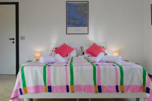 a bedroom with a large bed with pink and colorful pillows at Casa Gialla Soggiorno Panorama in Centro Storico in Dogliani