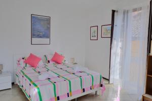 a white bedroom with a bed with pink pillows at Casa Gialla Soggiorno Panorama in Centro Storico in Dogliani