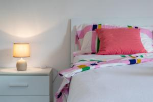 a bed with a pink pillow and a lamp on a night stand at Casa Gialla Soggiorno Panorama in Centro Storico in Dogliani +8 photos