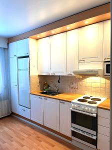 a kitchen with white cabinets and a stove top oven at After Work Escape with sauna and balcony in Joensuu