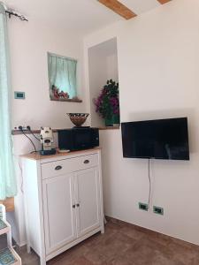 Una habitación con un armario blanco y un televisor en la pared. en Da Giorgia, en Forza dʼAgro
