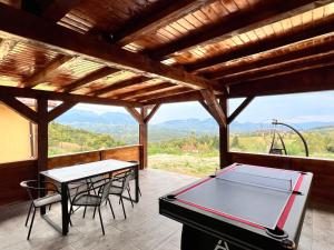 a ping pong table and chairs on a patio with a view at Casa Liniștea Munților in Fundata
