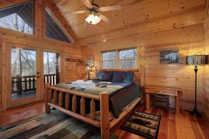 ein Schlafzimmer mit einem Bett in einer Blockhütte in der Unterkunft Whippoorwill Calling - Panoramic Mineral Bluff Cabin - Panoramic Views, Hot Tub, Nature Trail, Private Cul-De-Sac Home, Firepit, in Mineral Bluff