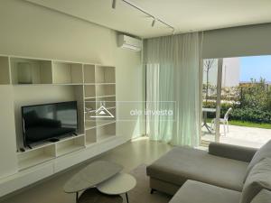 Una sala de estar con televisión y un sofá. en Green Coast 60 a, en Palasë