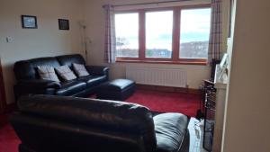 a living room with black leather furniture and a couch at Taigh Na Talia - 2 Sandholm in Mallaig