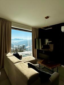 a living room with a couch and a large window at Bacówki Resort in Ochotnica Górna +212 photos