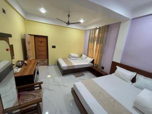 a hotel room with two beds and a desk at Hotel Mayur in Bihpuriāgaon +19 photos