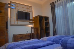 a bedroom with two beds and a flat screen tv at Casa De Leren in Ngabean