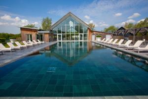 a swimming pool with chairs and a building at Minety Lake 64 ML64 Lower Mill Estate Cotswolds in Somerford Keynes