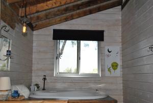 baño con bañera grande y ventana en wooden Edge Of The Village, en Ma'ale Gamla