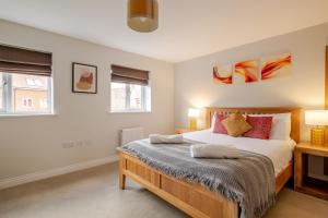 a bedroom with a bed and two windows at Comfy & stylish 4 bed house in Bedford