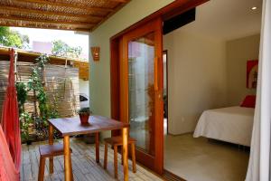Cette chambre comprend une table, un lit et une fenêtre. dans l'établissement Morada das Marés, à Arraial d'Ajuda