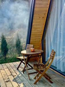 a wooden table and chairs on a porch with a view at Codrii Doftanei in Teşila +14 photos