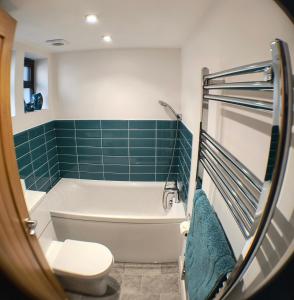 ein Badezimmer mit einer Badewanne, einem WC und grünen Fliesen in der Unterkunft Goviers Cottage in Sidmouth + 25 Fotos