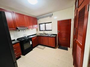a kitchen with wooden cabinets and a black stove at Jacobi Apartments in Kitwe