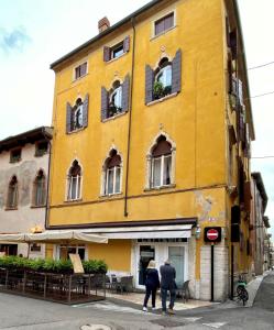 dos personas caminando en frente de un edificio amarillo en Ponte Pietra Lovely Home in Verona, en Verona