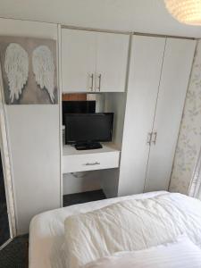 a bedroom with a bed and a tv and white cabinets at 243 Sealands in Ingoldmells