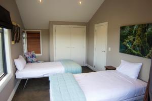 a bedroom with two beds and a couch at Ruru Lodge - Bed and Breakfast in Kinloch +4 photos