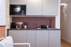 a kitchen with white cabinets and a microwave at Cosy air-conditioned Studio - Place de la Bourse in Bordeaux